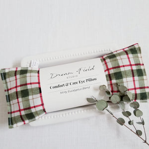 Eucalyptus mint blend eye pillow in red and green windowpane plaid fabric and sprig of eucalyptus leaves