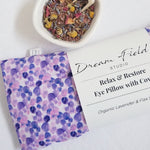 Organic lavender eye pillow with purple dot cotton cover and white bowl filled with herbs