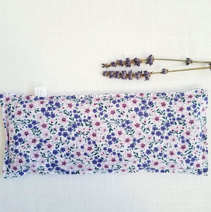 lavender eye pillow laid flat with 2 stems of lavender