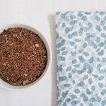 Closeup of blue spa dot print fabric and bowl of flax seeds and organic herb leaves