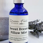 A close up  of Sweet Dream Pillow Mist in a blue glass bottle